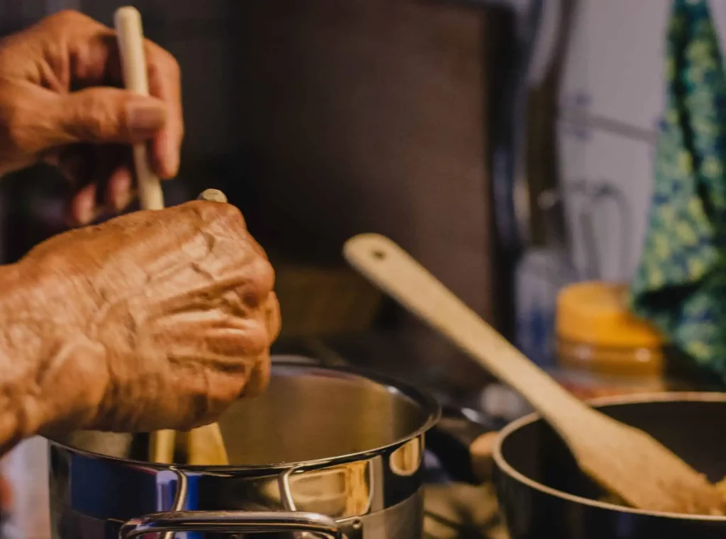 Hands stirring a cooking pot