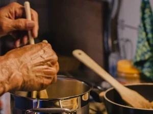 Hands stirring a cooking pot