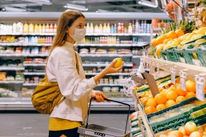 A woman selects items from a supermarket shelf