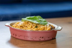 A dish of pasta with a basil leaf on top