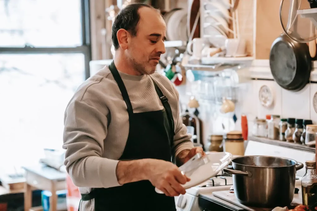 A man in an apron cooks in a kitchen