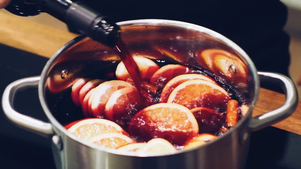 Red wine being poured into a cooking pot